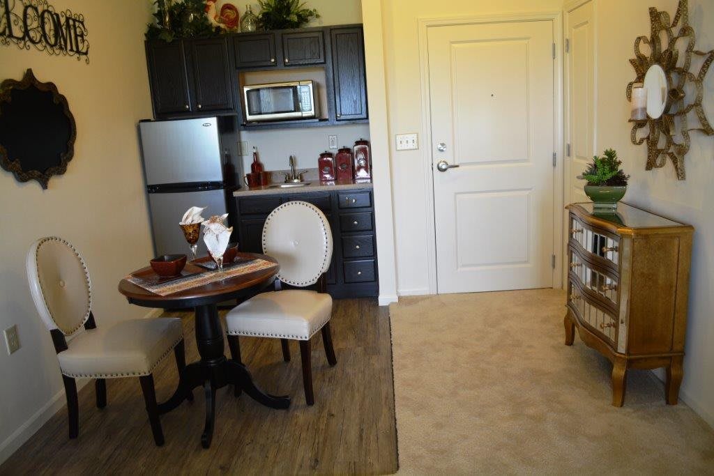 A small kitchen area with a dining table and two chairs, featuring a microwave and refrigerator.