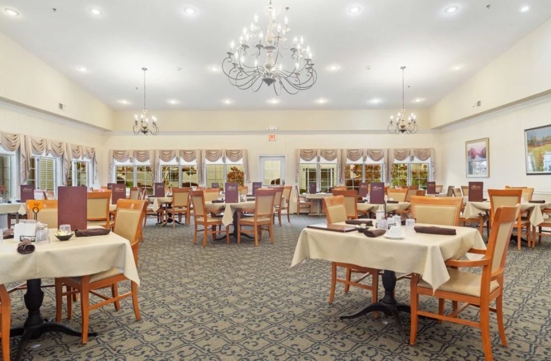 A spacious dining room with elegantly set tables and a large chandelier.