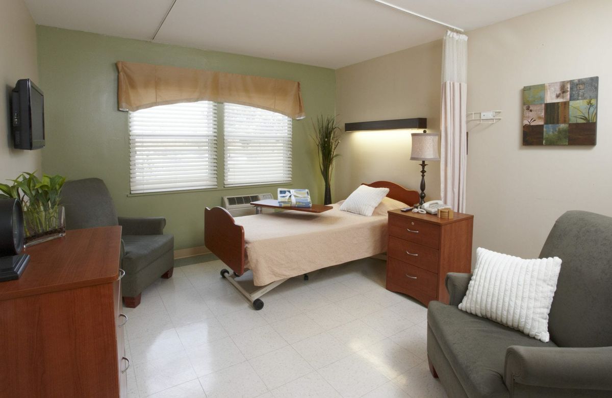 A hospital room with a bed and comfortable seating.