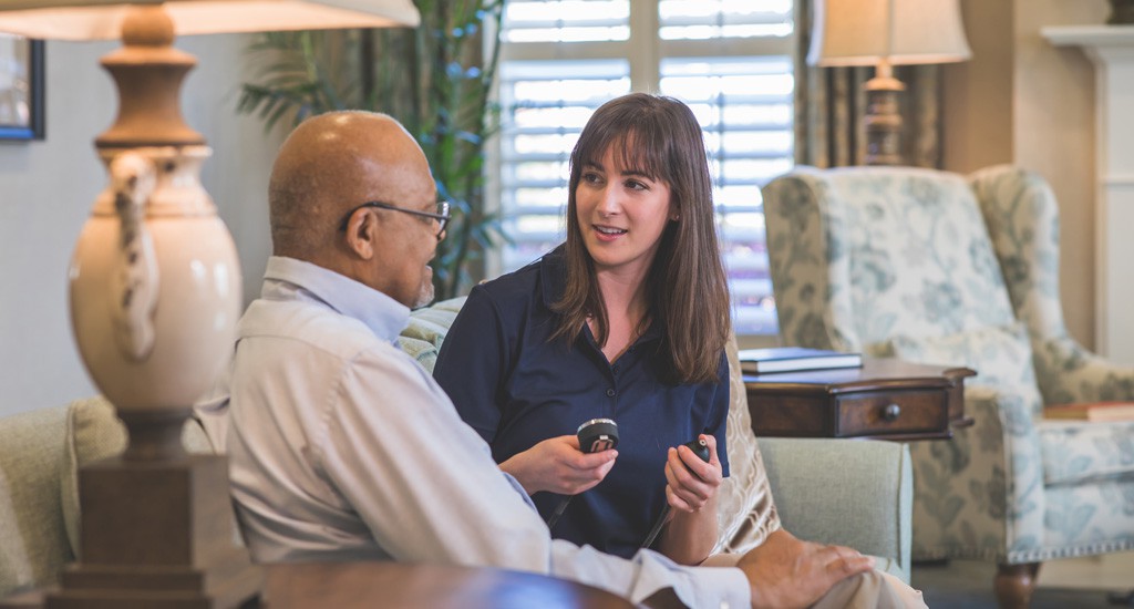 A woman and an elderly man having a conversation in a comfortable living room setting.