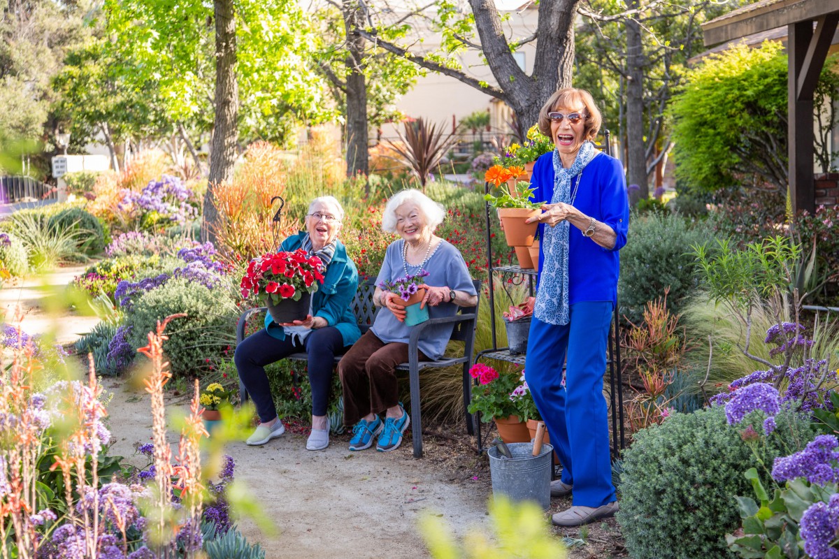 Three seniors enjoying a peaceful time in a colorful garden.