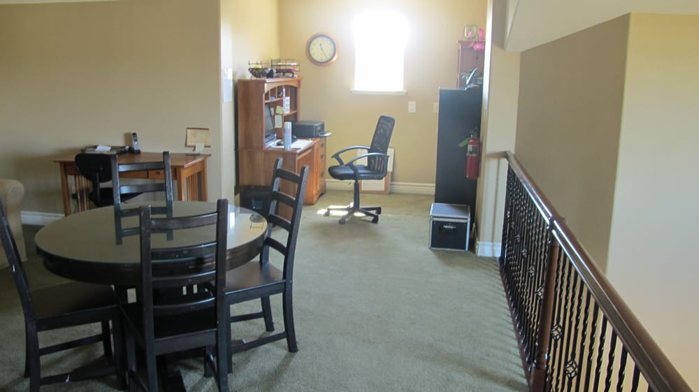 A home office space with a desk, chair, and circular table on a carpeted floor.