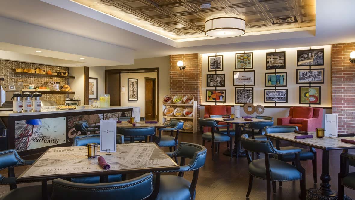 A cozy restaurant interior with elegant tables, chairs, and art-adorned walls.