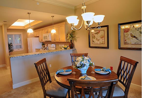 A cozy dining area with a round table set for four, adjacent to an open kitchen.