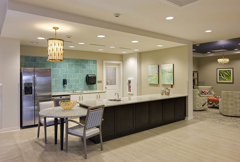 A modern kitchen space featuring a sleek countertop, seating area, and stylish light fixtures.