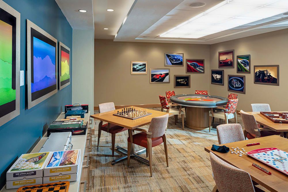 A stylish game room featuring chess and poker tables surrounded by modern artwork.