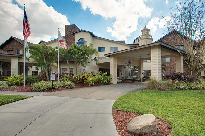 A welcoming building entrance with a driveway and lush landscaping.