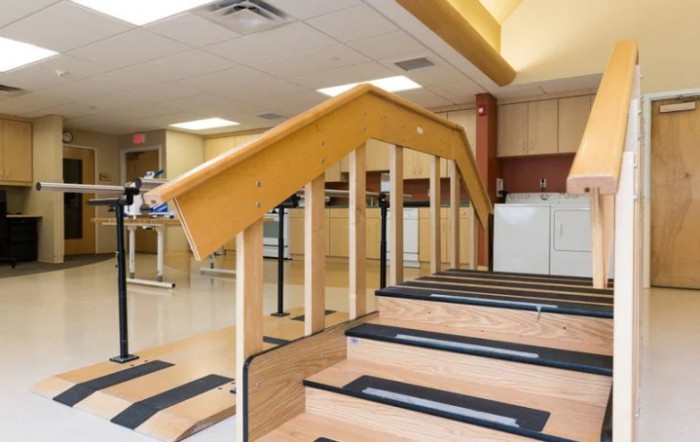 A physical therapy room with equipment and stairs for rehabilitation exercises.