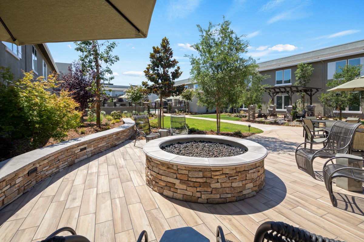 A beautifully landscaped outdoor patio featuring a central fire pit and lush greenery.