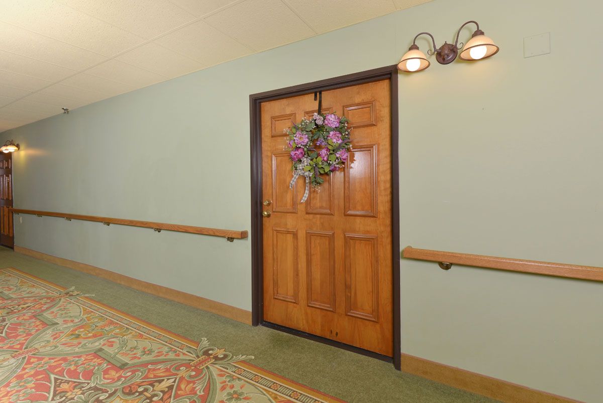 A decorated door in a hallway with a floral wreath and lighting fixtures above.