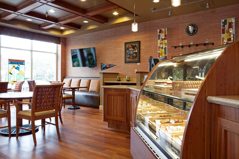 A cozy caf interior with a modern design, featuring a well-lit display case filled with pastries and a comfortable seating area.