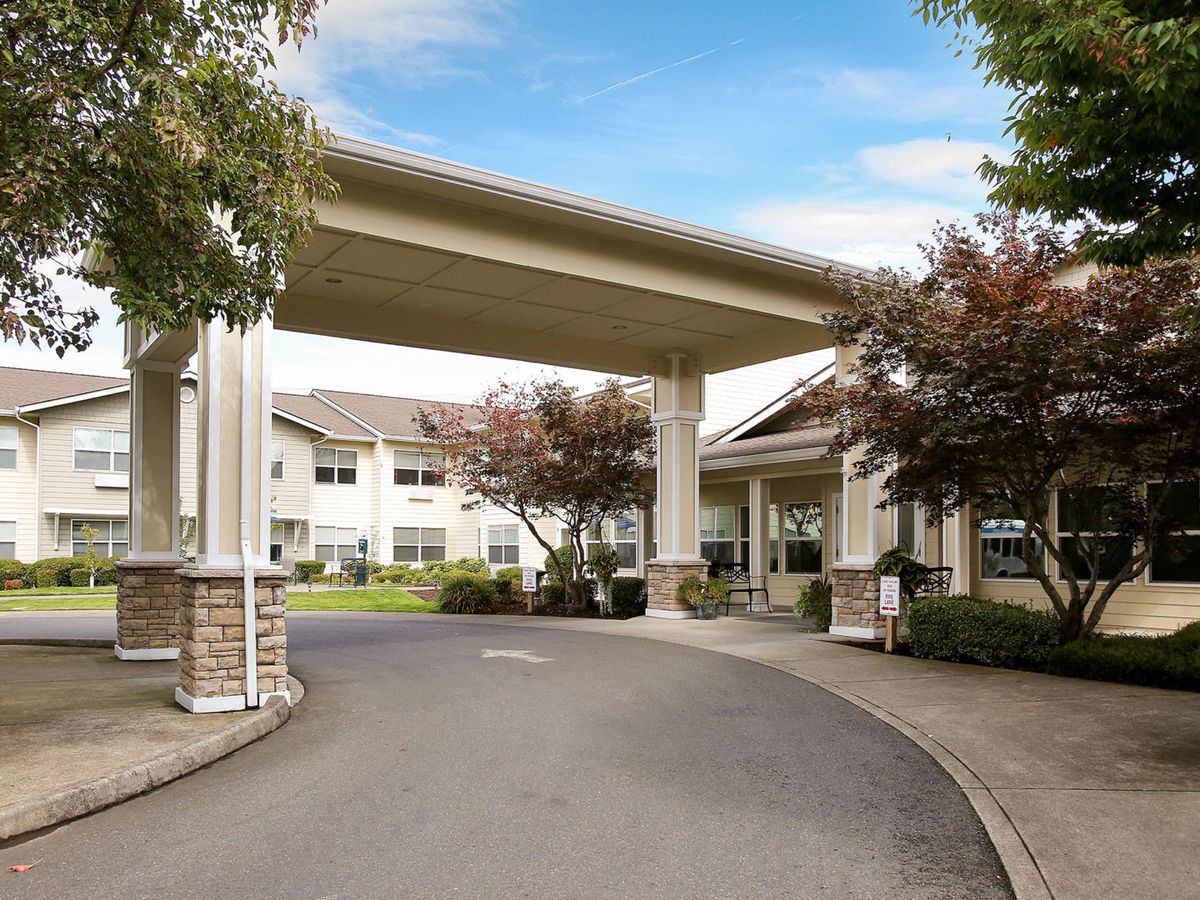 A covered entrance to a residential building with a driveway and landscaped surroundings.