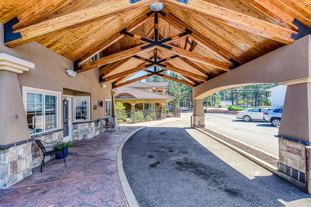 A covered driveway with wooden beams provides shade and shelter in front of the building.