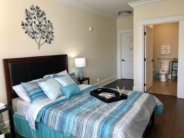 A modern bedroom with a striped bedspread, decorative pillows, and a wall art piece above the headboard.