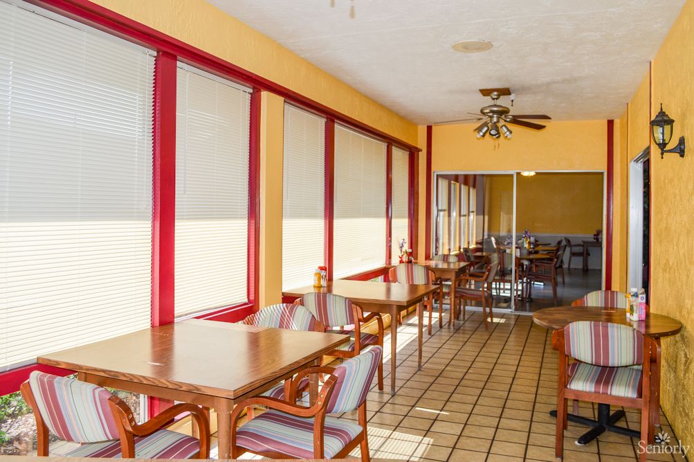 A bright restaurant dining area with large windows and neatly arranged tables and chairs.