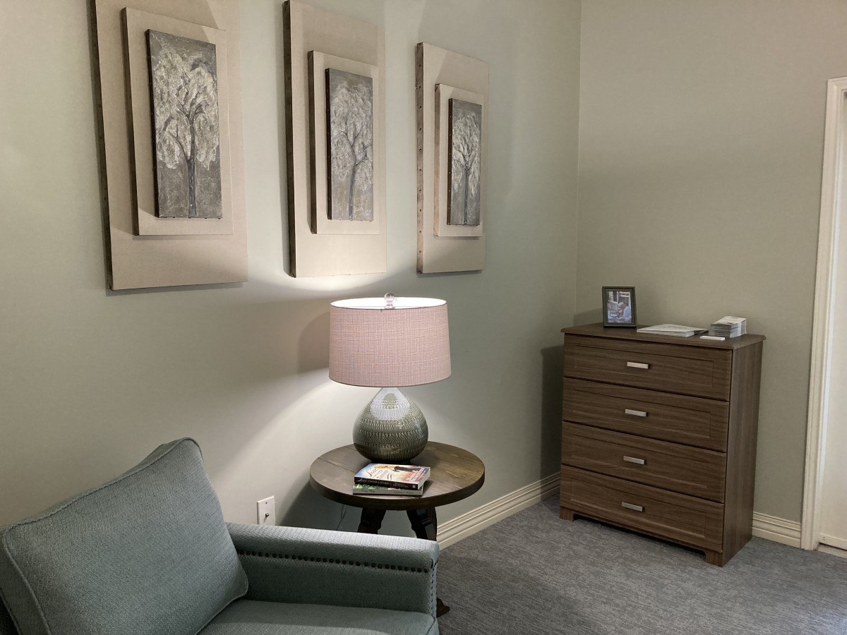 A cozy living room corner with a sofa, side table, lamp, and framed artwork.