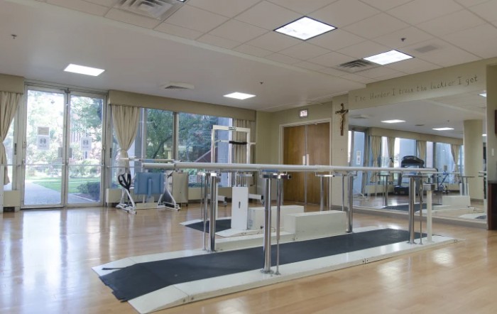 A rehabilitation center equipped with parallel bars and exercise equipment for physical therapy.