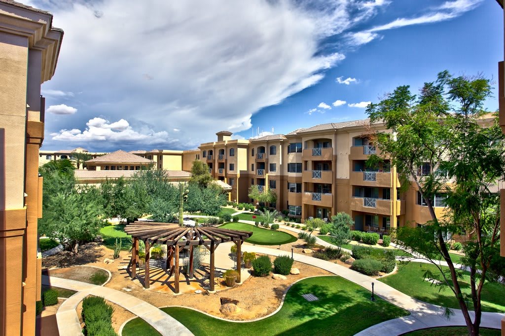 A scenic view of a resort with well-maintained gardens and lush greenery under a cloudy sky.
