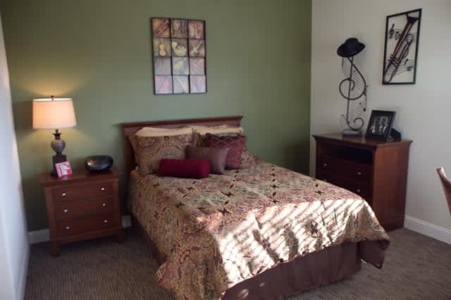 A cozy bedroom with a neatly made bed, nightstands, and warm decor.