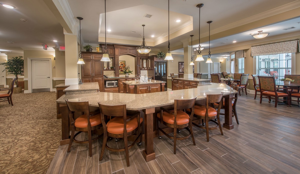 Spacious modern kitchen with a large countertop and seating, featuring pendant lighting and wooden accents.