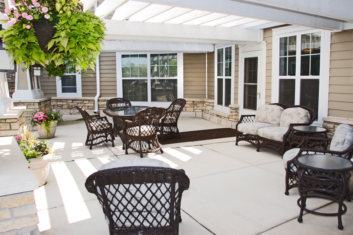 A patio area with wicker furniture and a pergola providing shade.