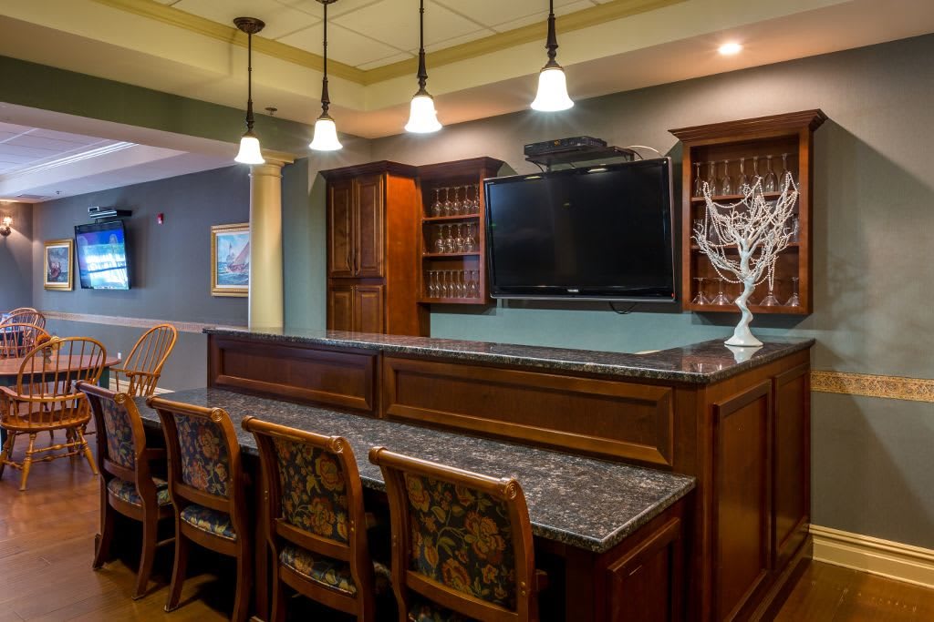 A stylish home bar with wooden cabinets, granite countertops, and pendant lighting.