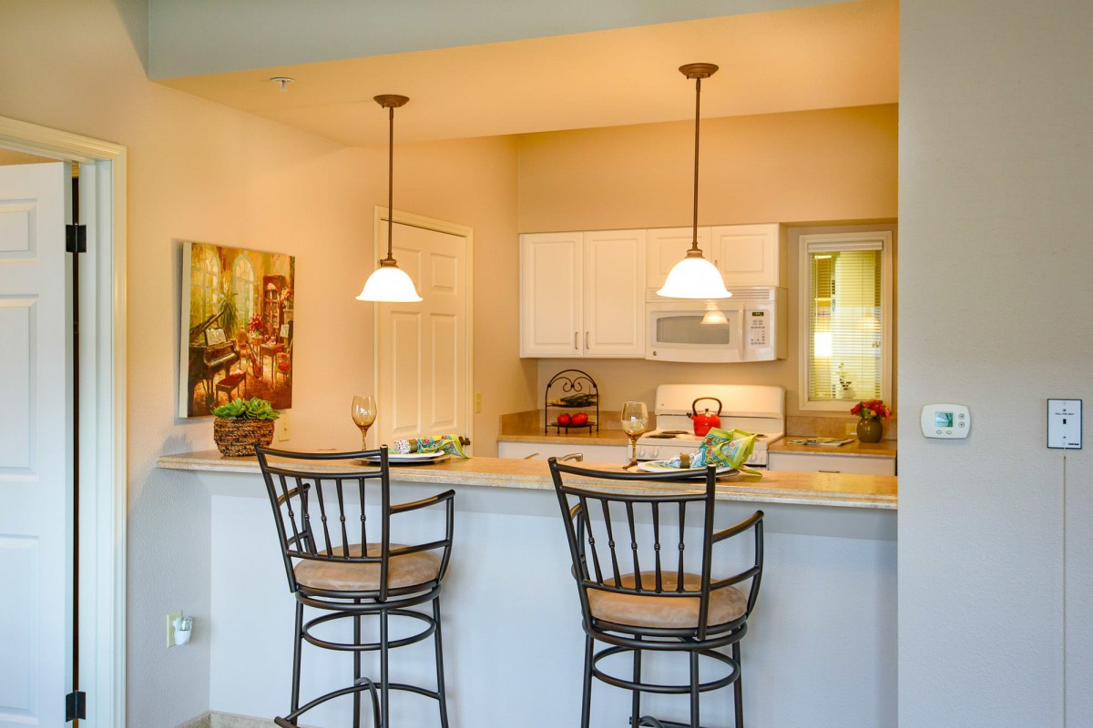 A modern kitchen with a cozy breakfast bar, featuring two elegant bar stools and warm pendant lighting.
