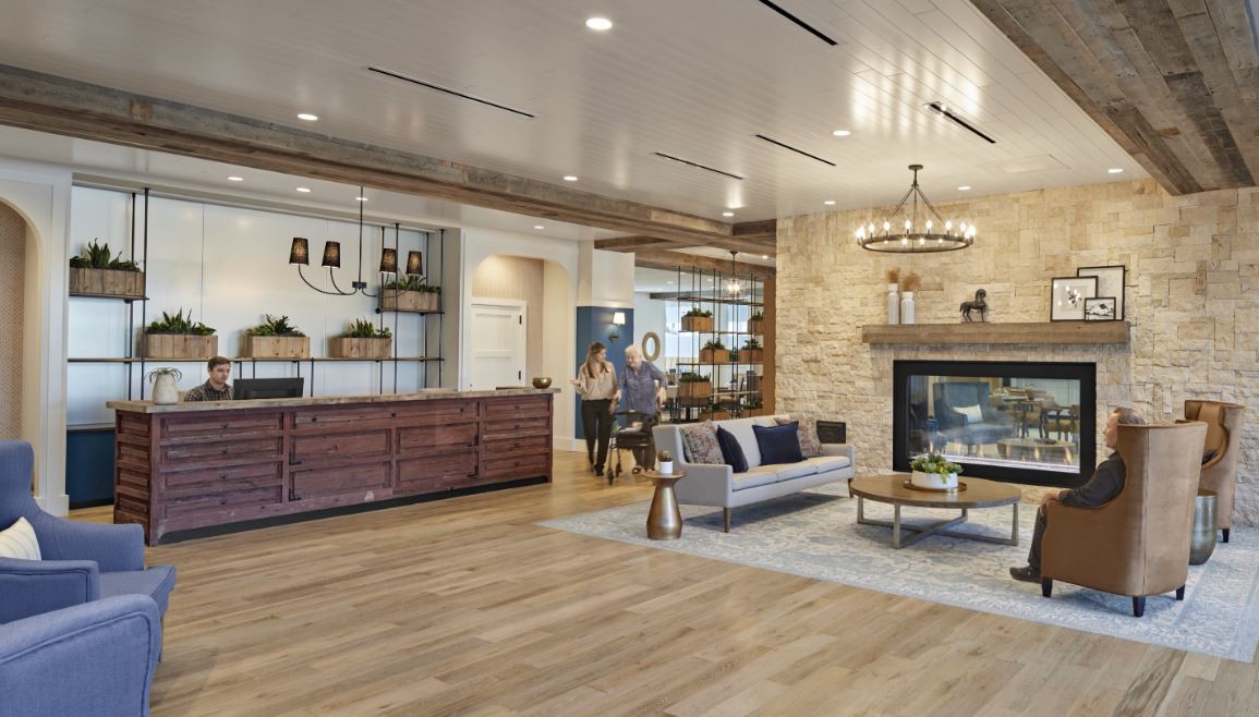 A modern living room featuring a stone fireplace, wood flooring, and elegant decor.