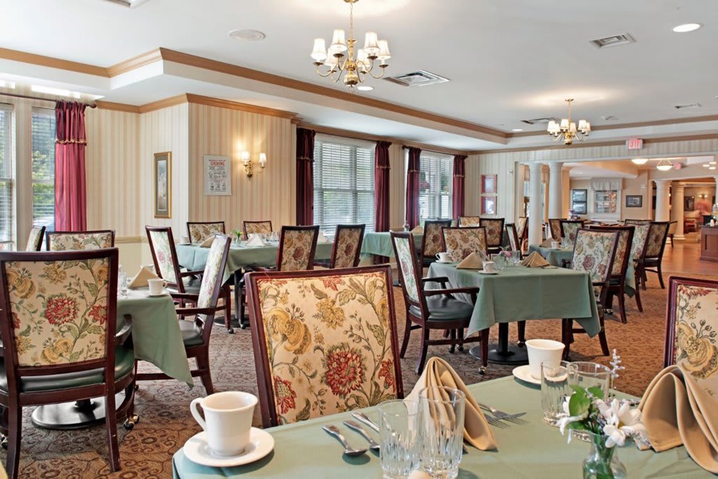 An elegant dining room with tables set for service and patterned chairs.
