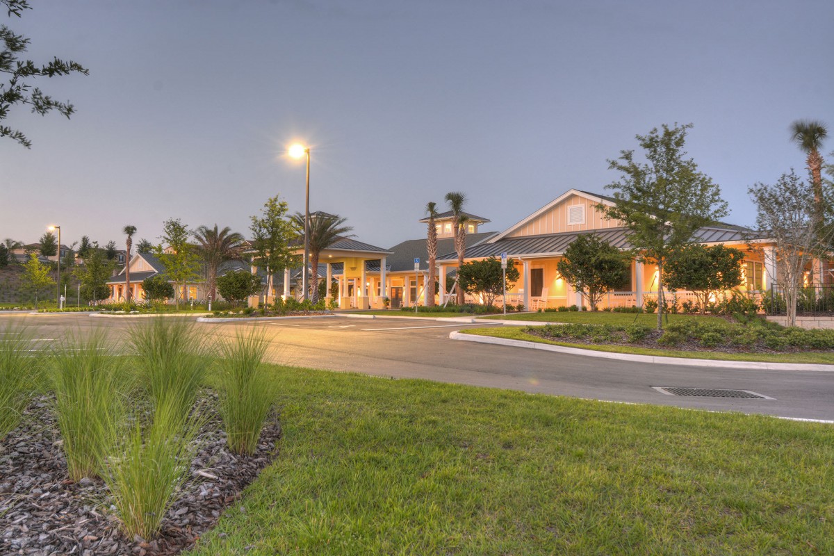 A well-lit building surrounded by trees and grass during the evening.
