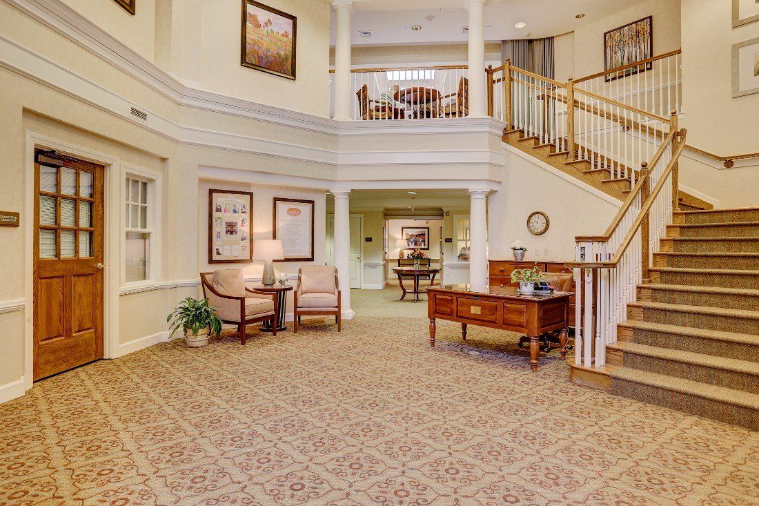 A spacious and elegant lobby area with a staircase, comfortable seating, and classic decor.
