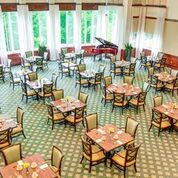 An elegant dining hall with neatly arranged tables and a grand piano.