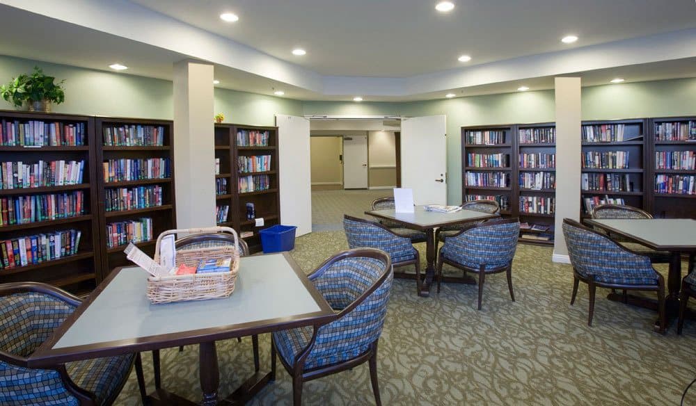 A cozy library reading area with tables, chairs, and bookshelves.