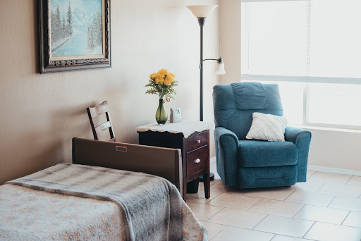 A cozy bedroom featuring a comfortable recliner, floral decor, and warm natural lighting.