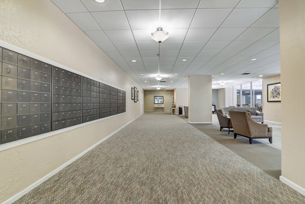 A modern hallway with mailboxes on the wall and a seating area at the end.
