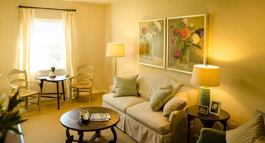 A cozy living room with a comfortable sofa, decorative lamps, and floral artwork on the wall.