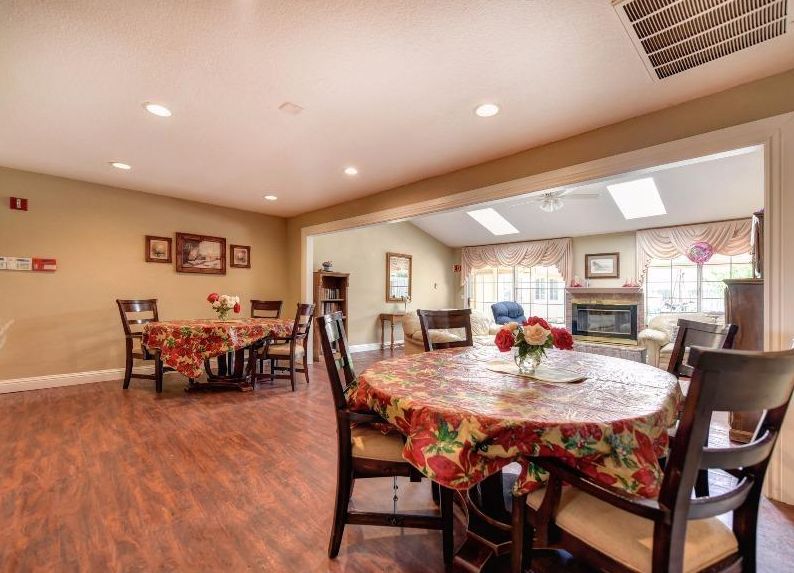 A cozy dining area with tables covered in colorful tablecloths, surrounded by wooden chairs and warm lighting.