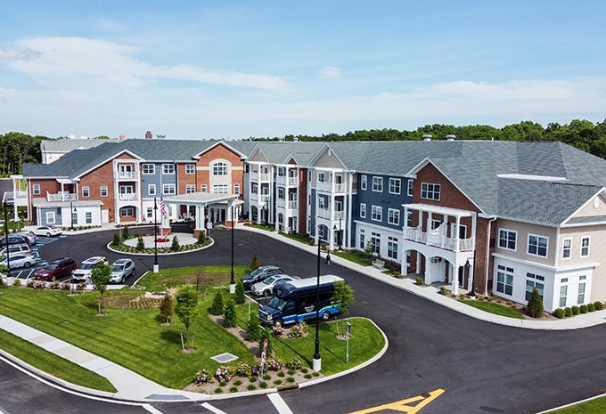 A modern residential apartment complex with landscaped gardens and a parking area.