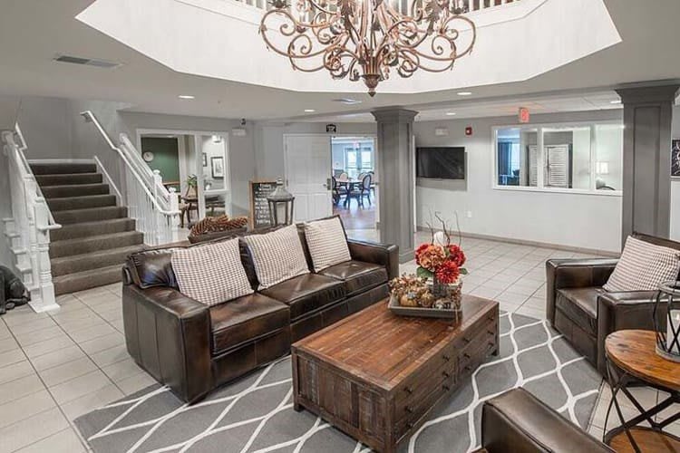 A cozy and modern living room with a leather sofa, wooden coffee table, and an elegant chandelier.