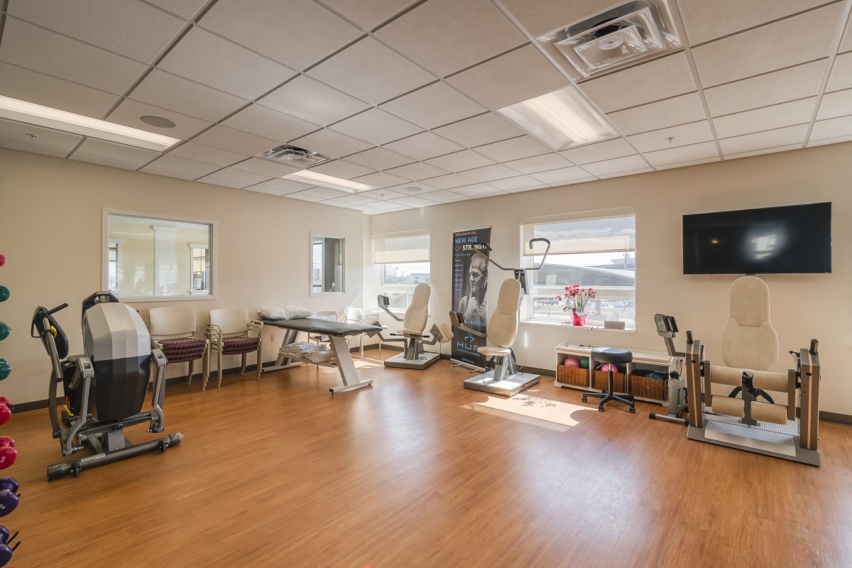 A well-lit fitness center with exercise equipment and ample space.