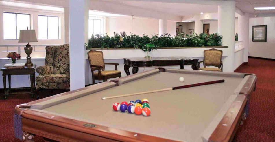 A billiards room featuring a pool table with colorful balls and cue sticks, surrounded by elegant furniture and decor.