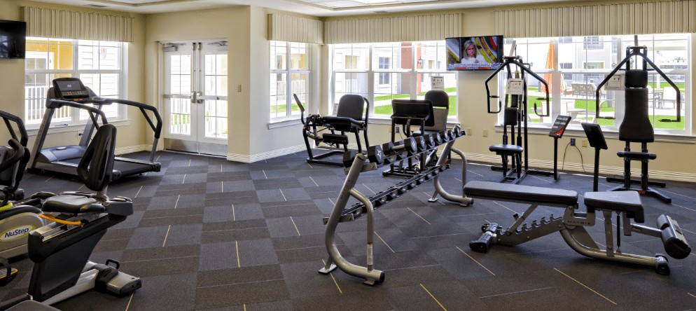 A clean and modern gym with exercise equipment and dumbbells.