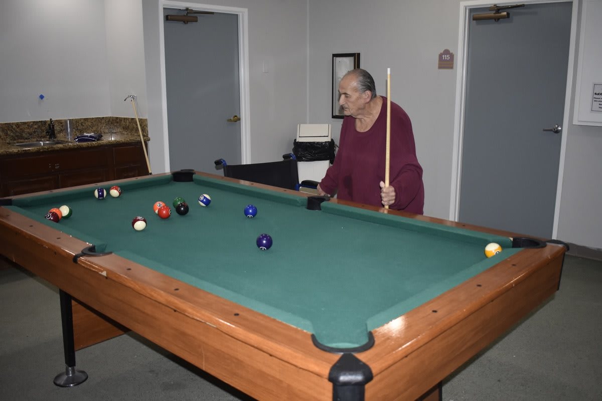 A person playing billiards indoors using a cue stick.
