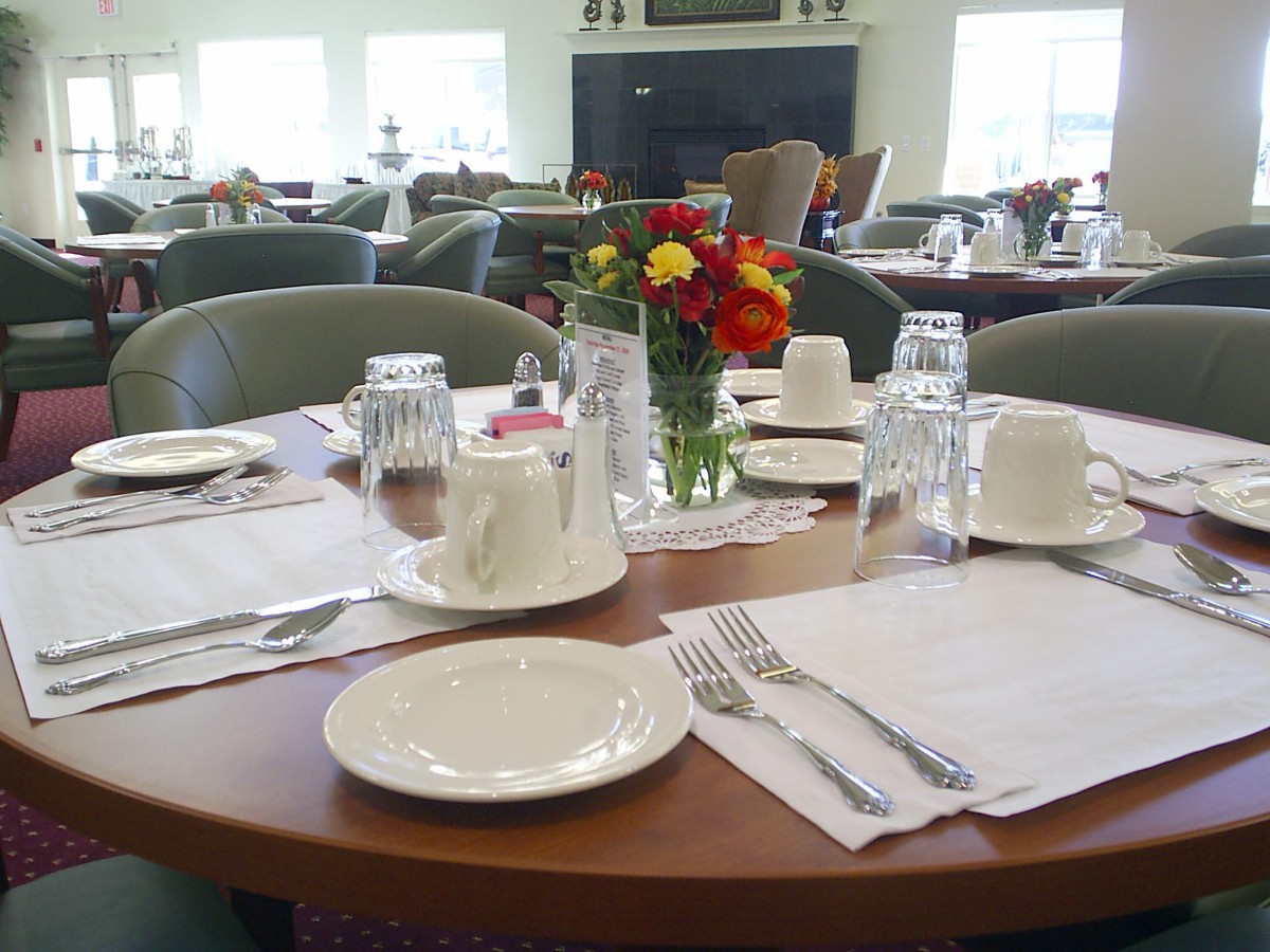 A neatly set dining table with flowers in a restaurant.
