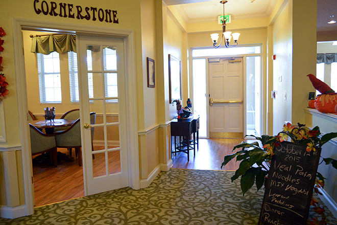 A well-lit hallway with doors, furniture, and decorative plants.