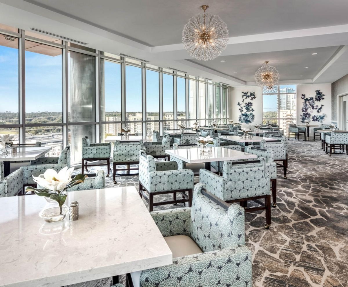 A modern restaurant with elegant decor and large windows offering a city view.