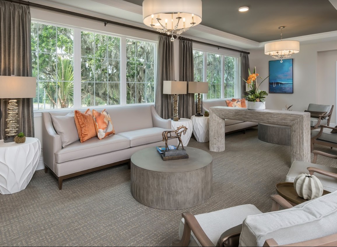 A modern living room with large windows, stylish sofas, a round coffee table, and decorative lighting.
