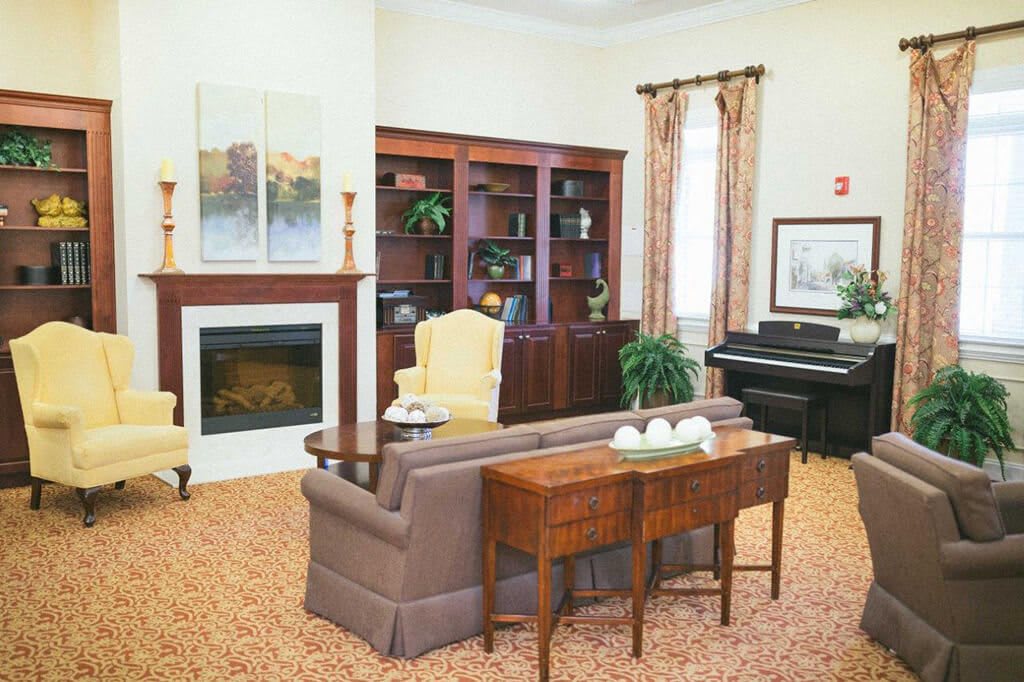 A cozy living room featuring a fireplace, bookshelves, and a piano.