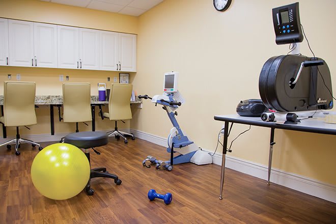 A rehabilitation room equipped with a therapy ball, dumbbell, and various medical devices.