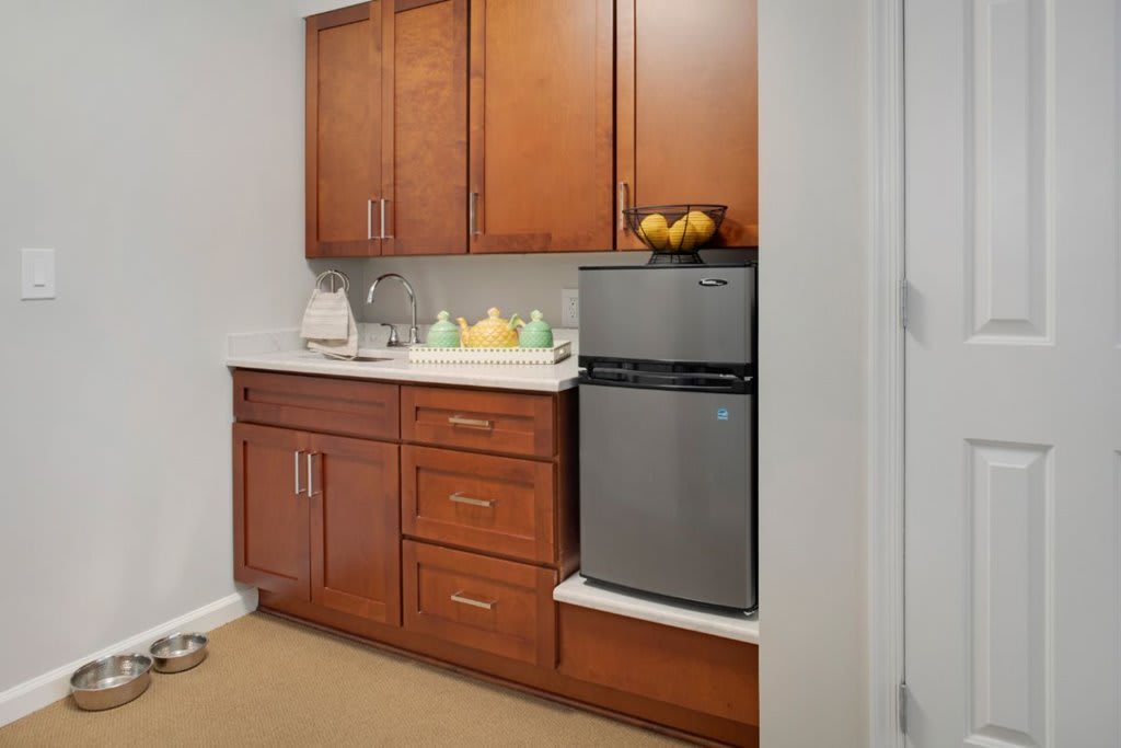 A compact kitchen area featuring wooden cabinets, a small refrigerator, and a countertop with a sink.